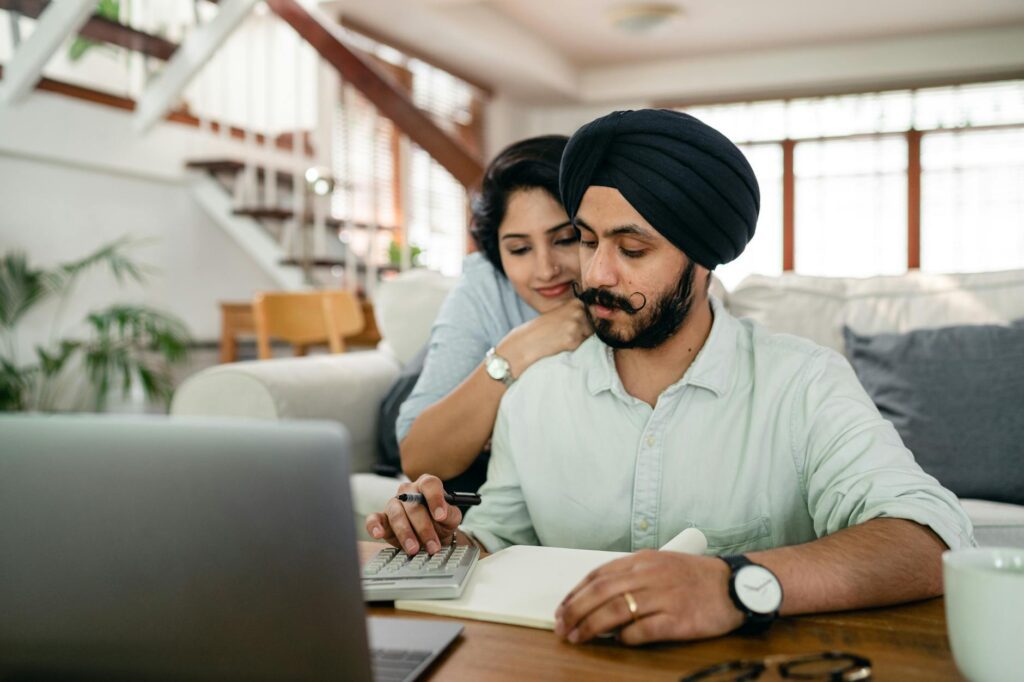 young indian couple counting bills on calculator