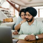 young indian couple counting bills on calculator